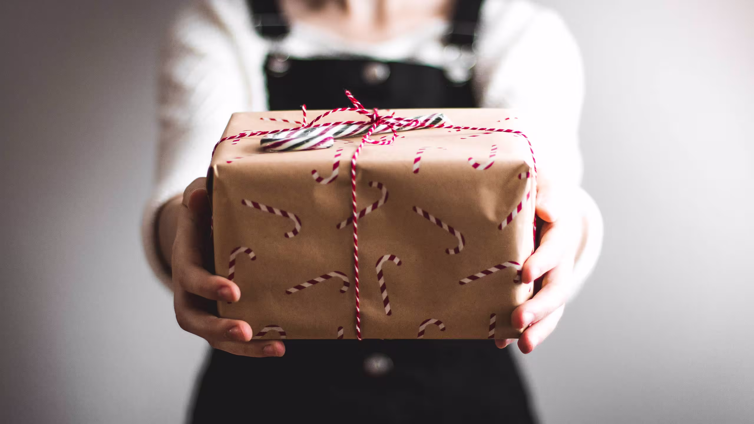 a person holding a holiday-wrapped package with candy canes